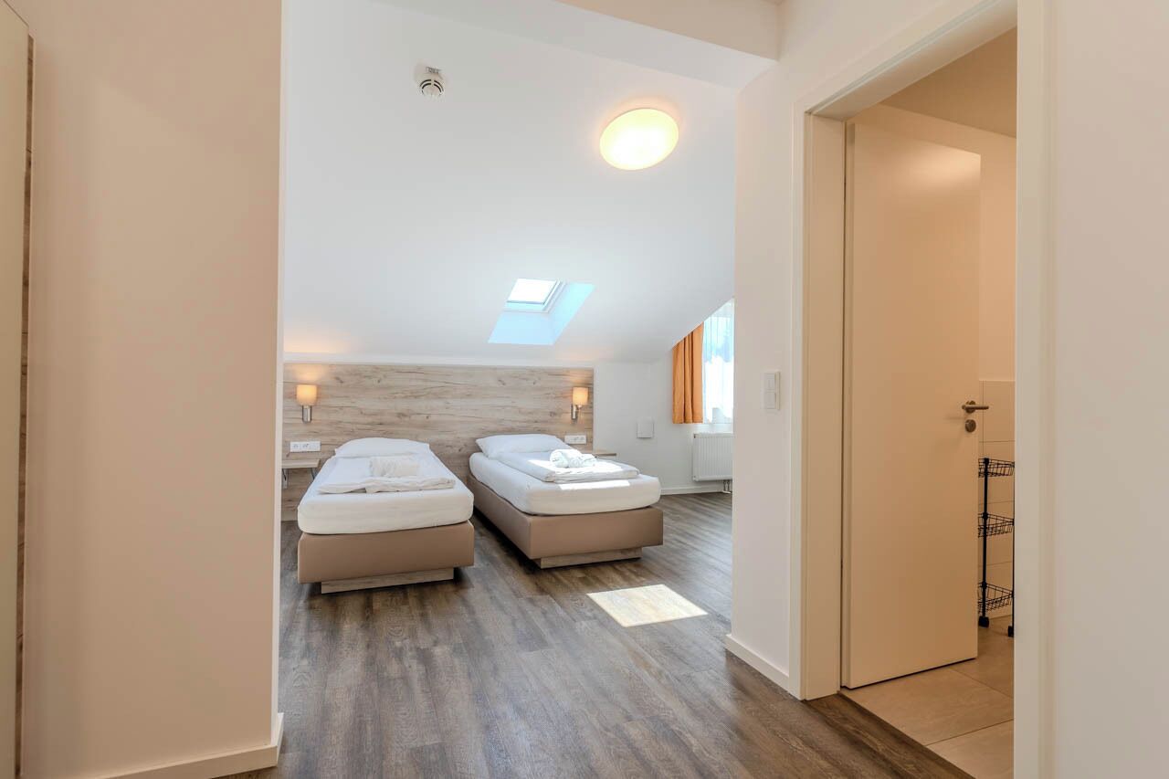 Une chambre moderne avec deux lits, une lucarne et un plancher en bois.
