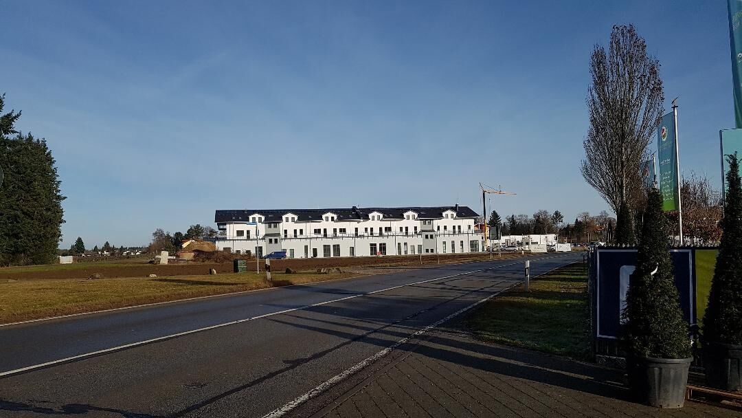 A long, straight road with a white building in the distance.