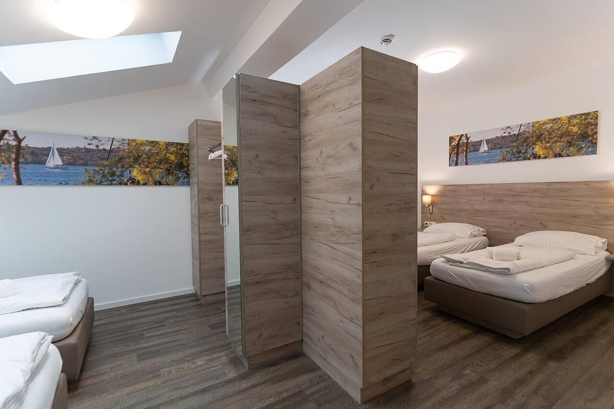 A modern hotel room with a large bed, a walk-in closet, and a skylight.
