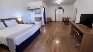 A hotel room with a bed, desk, chair, television, and a wardrobe. - Vitoria Palace Hotel (Lavras)