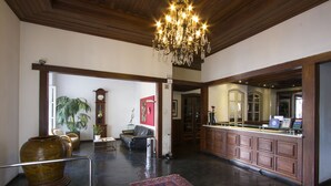 A spacious lobby with a chandelier, a large vase, a sofa, and a reception desk. - Vitoria Palace Hotel (Lavras)