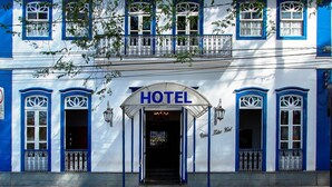 A hotel facade with a prominent entrance, multiple windows with decorative frames, and a tiled roof. - Vitoria Palace Hotel (Lavras)