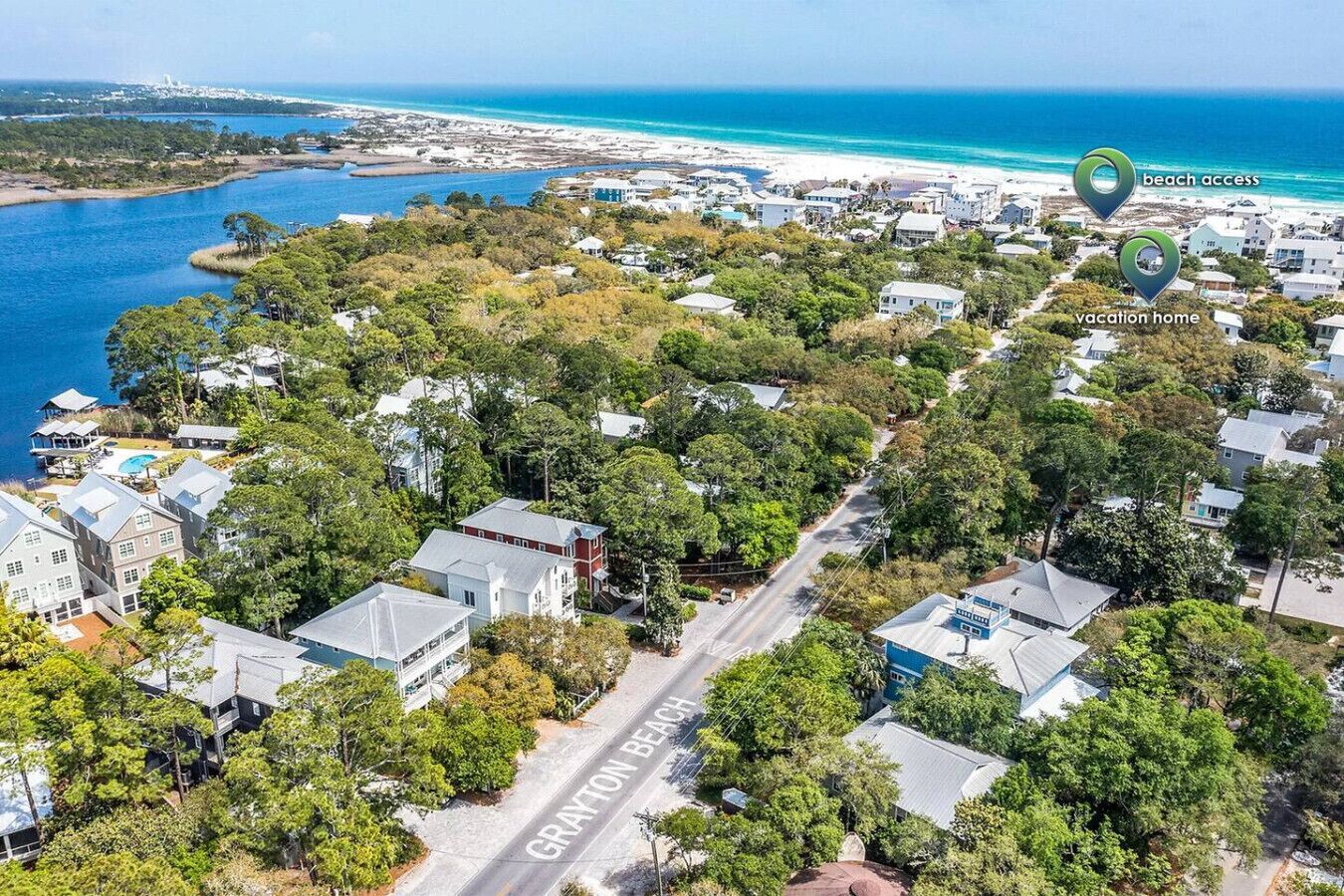 Vue aérienne d’un quartier résidentiel avec des maisons, une route portant l’inscription « GRAYTON BEACH » et une plage en arrière-plan.