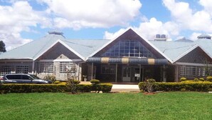 A large, modern building with a symmetrical design, featuring a central glass facade and multiple roof sections. - Eldoret Adventist Guest House (Eldoret)