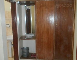 Wardrobe with mirror and storage, featuring a sink and bathroom area nearby.