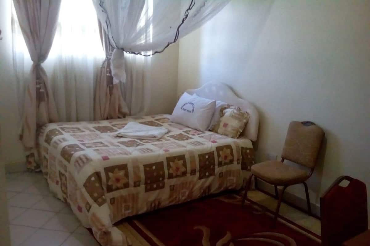 A bedroom with a bed, a chair, and a red rug.