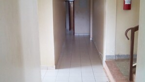 A corridor with tiled flooring, a fire extinguisher mounted on the wall, and a wooden handrail on the right. - Eldoret Adventist Guest House (Eldoret)