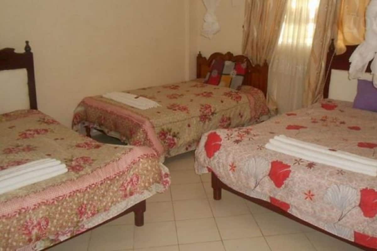 A room with two single beds, each with a floral-patterned bedspread and a neatly folded white towel.