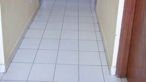 A long, narrow hallway with tiled flooring and wooden doors on both sides. - Eldoret Adventist Guest House (Eldoret)