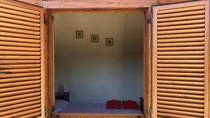 A wooden room with a bed, a nightstand, and a wall with three framed pictures.