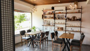 A dining area with a wooden table and chairs, a bookshelf with various items, and a ceiling with hanging lights. - Galata Dream Hotel (Istanbul)