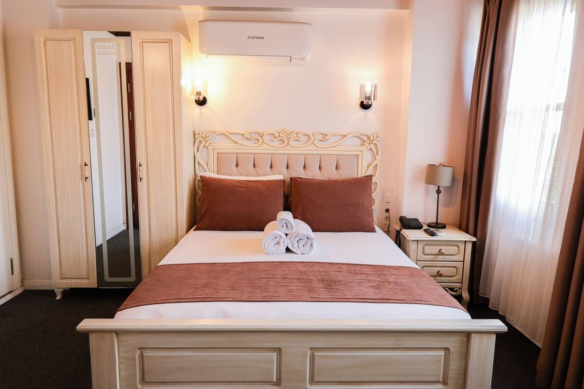 Ein Hotelzimmer mit einem Bett, zwei Wandleuchten, einem Nachttisch mit Lampe, einem Telefon und einem Kleiderschrank.