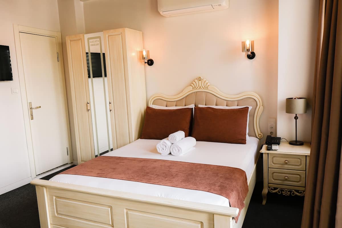 Ein Hotelzimmer mit Bett, Schrank, Nachttisch und Lampe.