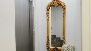 A hallway with a marble floor, a gold-framed mirror, a white flower arrangement, and a closed elevator door. - Galata Dream Hotel (Istanbul)