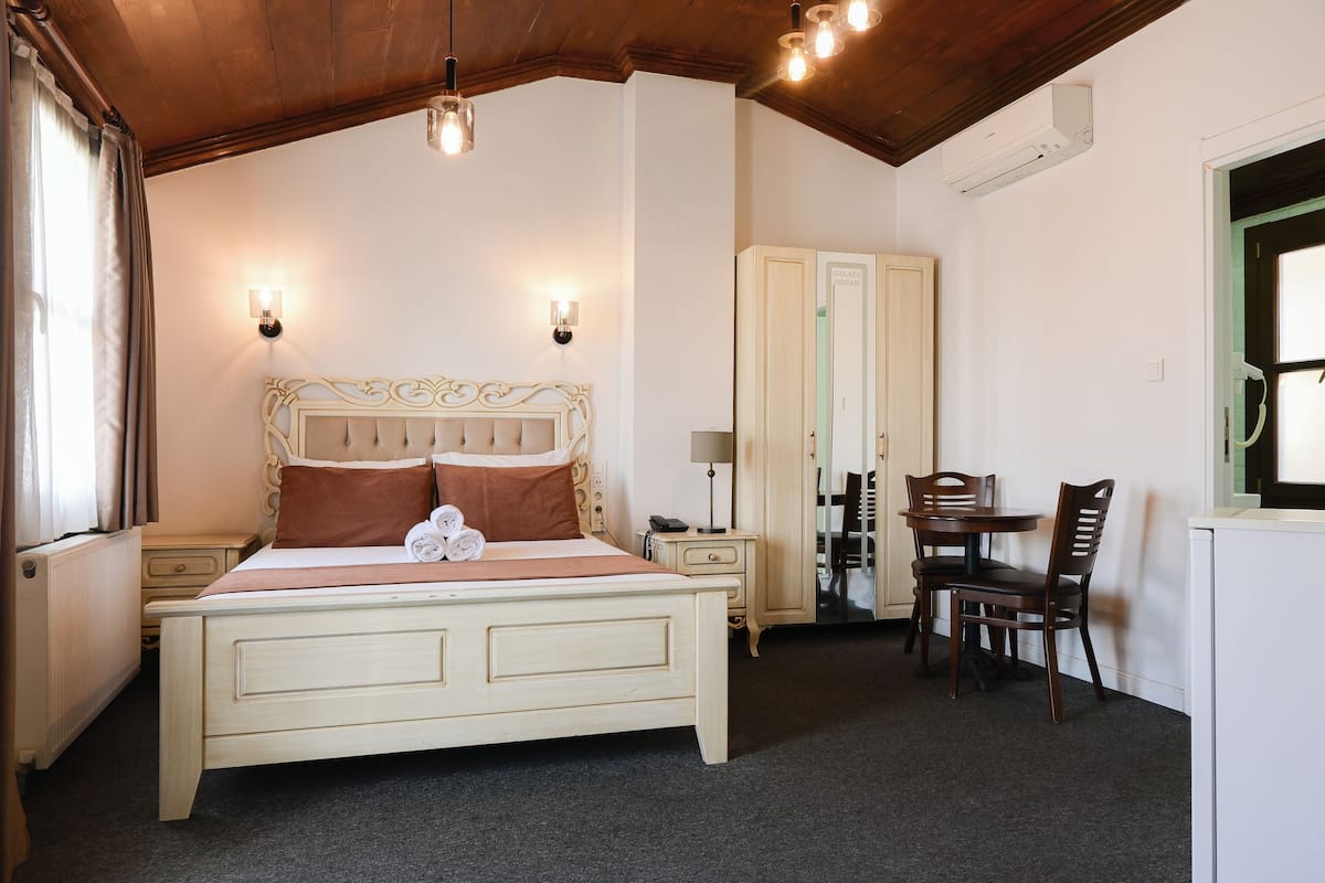 Ein Schlafzimmer mit einem Bett, Nachttischen, einem Schreibtisch mit Stuhl und einer Klimaanlage.