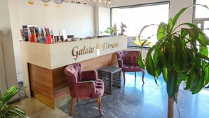 A reception desk with a wooden finish, two purple armchairs, and a large potted plant. - Galata Dream Hotel (Istanbul)