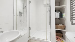 Un bagno moderno con doccia vetro, lavandino bianco e mensole con articoli da toilette.