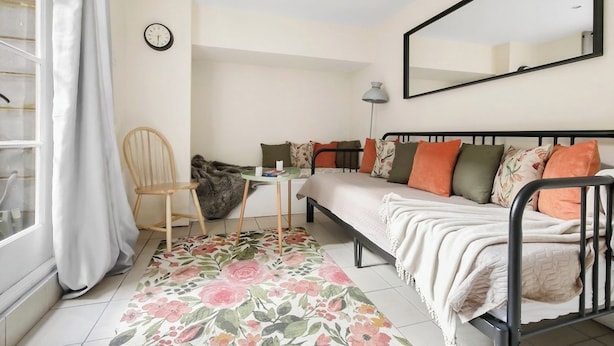Una camera da letto con un letto, una sedia, una scrivania, uno specchio e una finestra con tende.