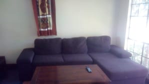 A living room with a dark-colored sofa and a wooden coffee table. - Flo Garden Resort (Ruiru)