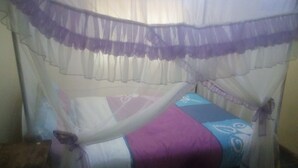 A bed with a canopy, a bedside table, and a wall-mounted shelf. - Flo Garden Resort (Ruiru)