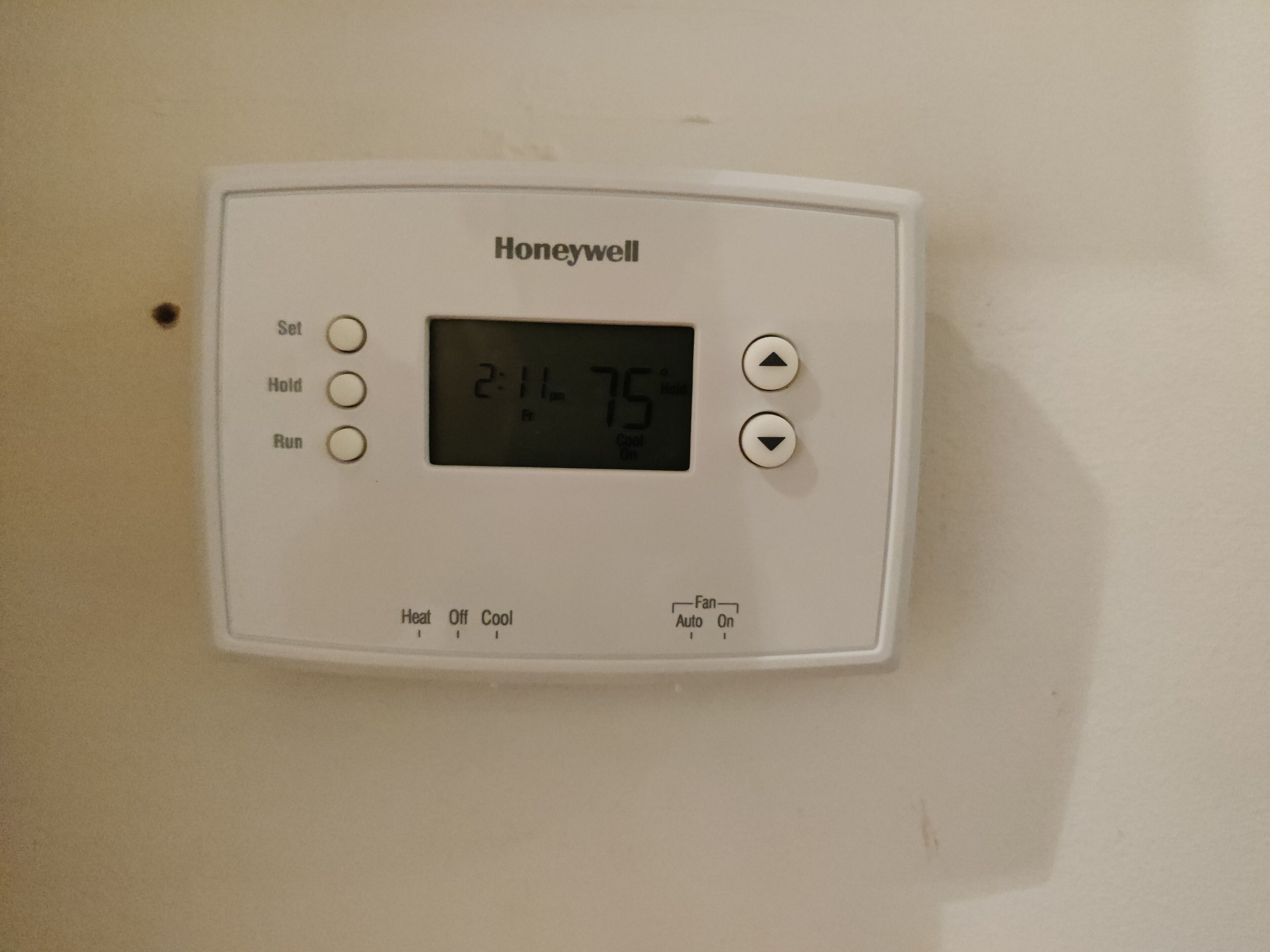 Ein Honeywell-Thermostat an einer Wand montiert, zeigt 24 Grad Celsius an und hat Bedienelemente für Heizung, Gebläse und weitere Einstellungen.