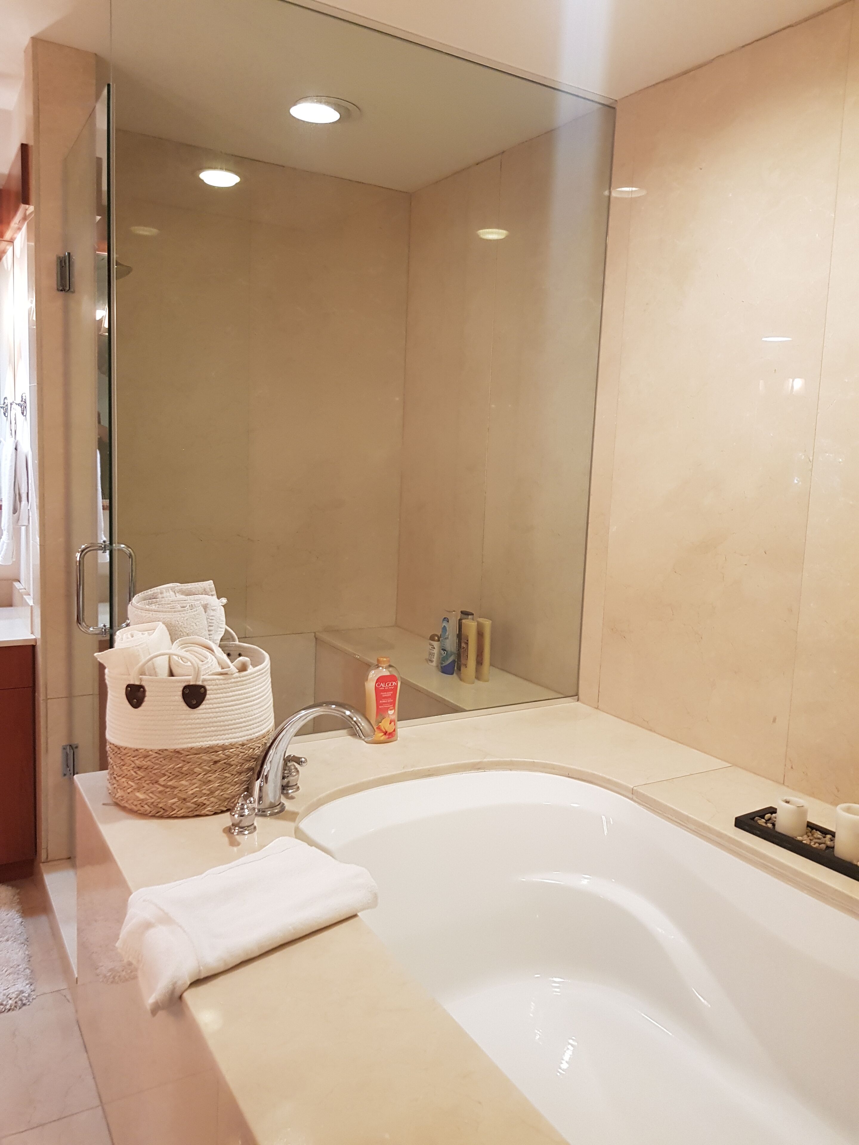 Une salle de bain moderne dotée d’une grande baignoire, d’une douche à parois de verre et d’un meuble-lavabo avec des articles de toilette.
