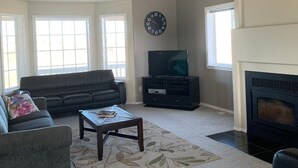 A living room with a sofa, coffee table, fireplace, TV stand, and a ceiling fan. - Lovely house on the Snake River that is minutes from CJ Strike Reservoir ! (Bruneau)