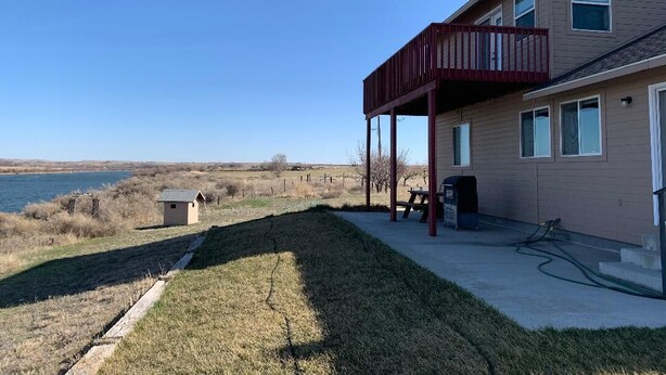 A two-story house with a covered patio, a small shed, and a view of a body of water. - Lovely house on the Snake River that is minutes from CJ Strike Reservoir ! (Bruneau)