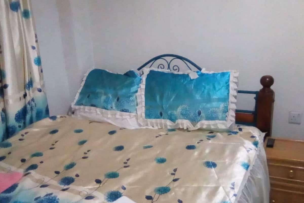 A bed with a floral bedspread, a wooden headboard, and a nightstand with drawers.