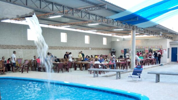 A pool area with a water feature, outdoor seating, and a covered section with tables and chairs. - Hotel Porto Bello (Caico)