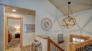 Un hall d’entrée spacieux avec un plancher en bois, un escalier doté de rampes en bois et un luminaire au plafond.