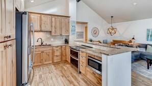 Une cuisine moderne avec des meubles en bois, un grand îlot central et un coin repas comprenant un canapé et une table.