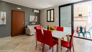 Una sala de estar moderna con comedor, un sofá, una mesa con sillas y un balcón con vistas.