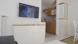 A modern kitchen with white cabinets, a microwave, and a wooden countertop.