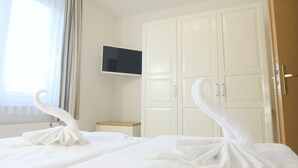 A hotel room with a bed, a TV mounted on the wall, and a wardrobe.