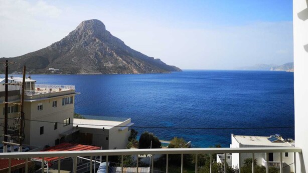 A view of a coastal area with a prominent mountain in the background and a clear blue sea.