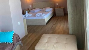 A bedroom with a bed, bedside tables, a nightstand, and a curtain.
