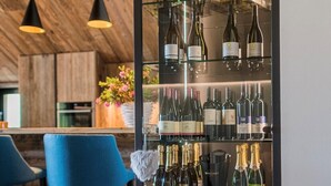 A modern bar area with a wine display, blue bar stools, and wooden flooring. - Chalet 'Chalet Ortles' with Lake View, Private Terrace, and Wi-Fi (Sankt Valentin auf der Haide)