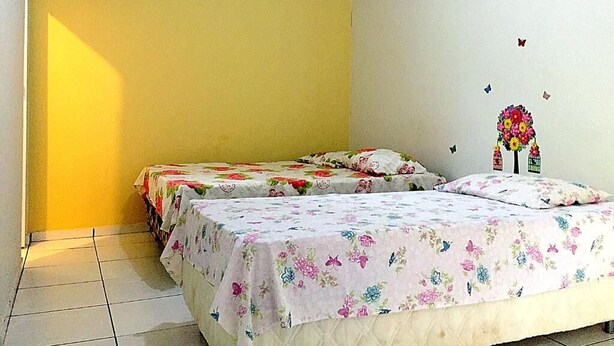 Une chambre avec deux lits, des murs jaunes et une couvre-lit à motifs floraux.