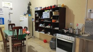Une cuisine compacte comprenant une table à manger, des chaises, un four à micro-ondes, une cuisinière et un réfrigérateur.