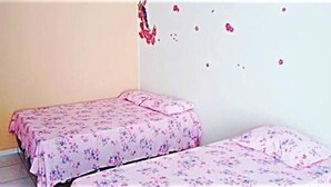 Une chambre avec deux lits, chacun recouvert d’une couvre-lit à motifs floraux.