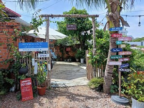 A rustic entrance with a wooden archway, a signboard for a homestay, and multiple directional signs. - Bot Bien Homestay (Mui Ne)
