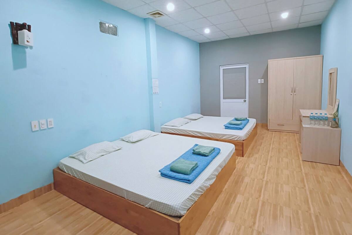 A room with two beds, a wardrobe, a desk with a mirror, and a water dispenser.