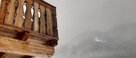A wooden balcony with a view of a snowy mountain range.