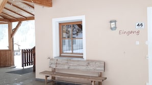 Un banco de madera frente a un edificio con una ventana y un letrero en la pared que dice 'Eingang'.