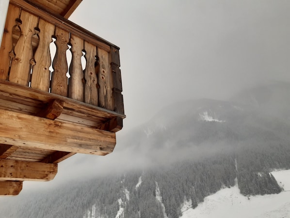 Un balcón de madera con vistas a una cadena montañosa nevada.