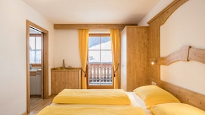 Una habitación con cama, cabecera de madera, ventana con cortinas y vista a un paisaje nevado.