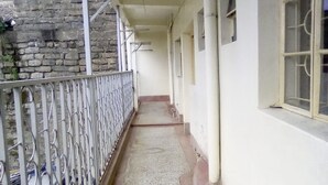 A narrow corridor with a metal railing on one side and windows on the other. - Haqy Guest House (Nakuru)