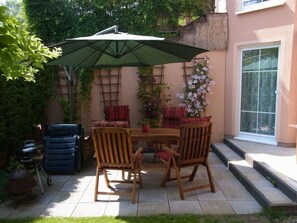 A patio with a table and chairs, a grill, and a covered umbrella.