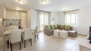 A modern apartment with a dining area, a sofa set, and a kitchen.